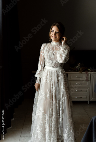 a positive bride in a beautiful wedding dress with lace is in a hotel room and is waiting for a meeting with the groom. beauty wedding day.