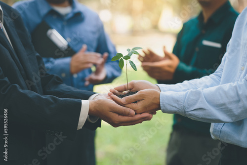 Unity of businessmen and community together holding small plant © Pcess609