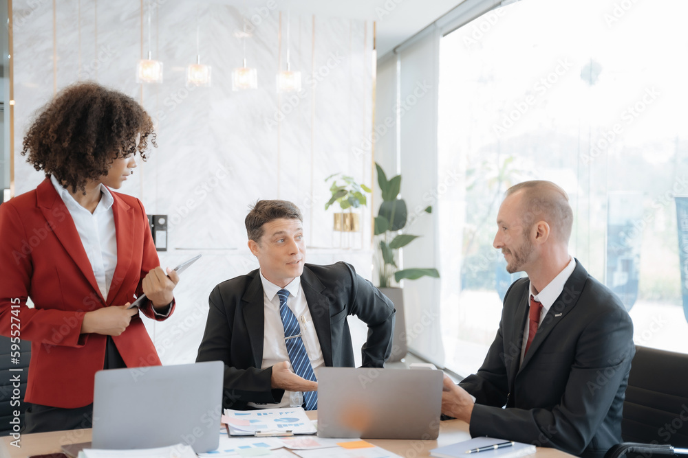 Mature business leader consultant talking to team of diverse colleagues listening to white CEO. Group project manager negotiating in the boardroom at a meeting. Mature business leader consultant talking to team of diverse colleagues listening to white CEO. Group project manager negotiating in the boardroom at a meeting.