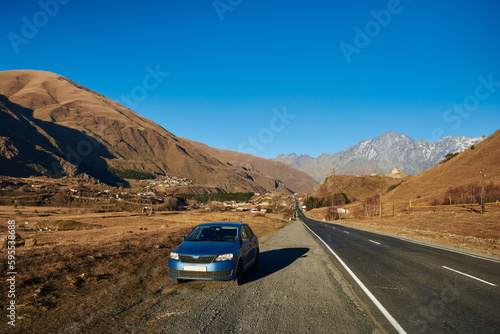 beautiful mountain landscape. a blue car is parked on the side of a winding mountain road. travel by car.