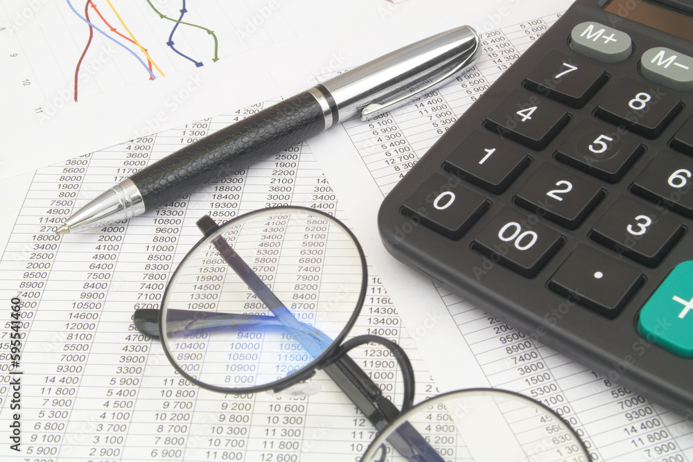 Round glasses, black pen and calculator on statements data. Round glasses, black pen and calculator on statements data.