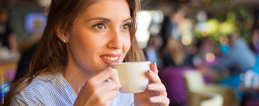 Young smiling woman drinking coffee in the coffee shop Young smiling woman drinking coffee in the coffee shop