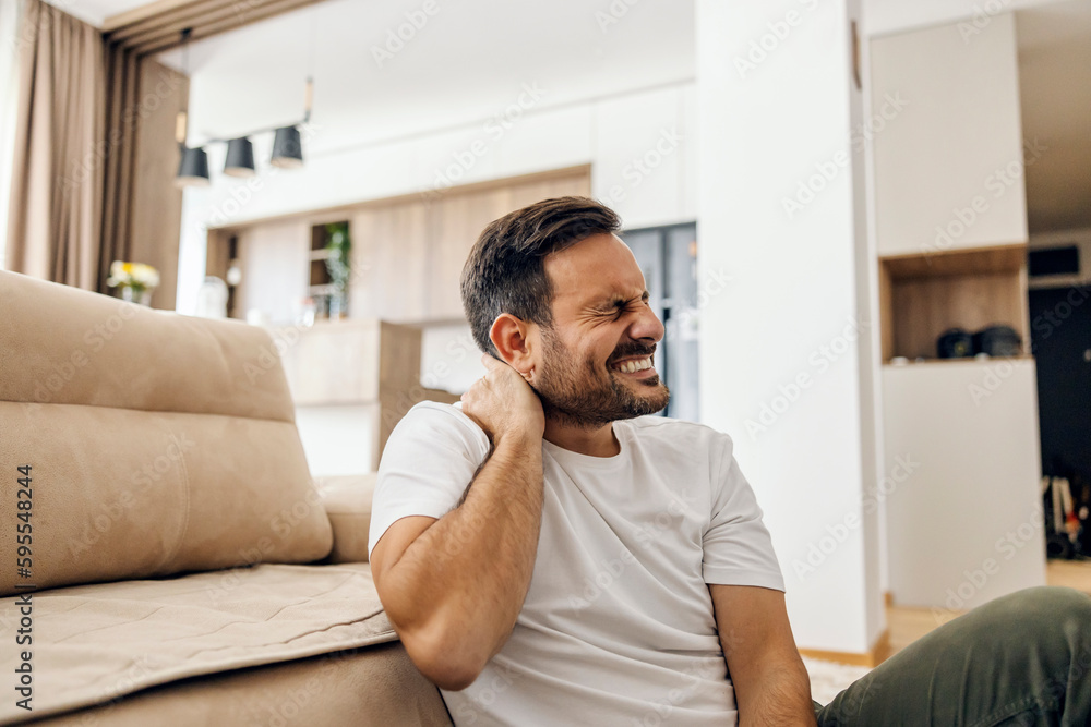 A man sits at home and has neck pain.