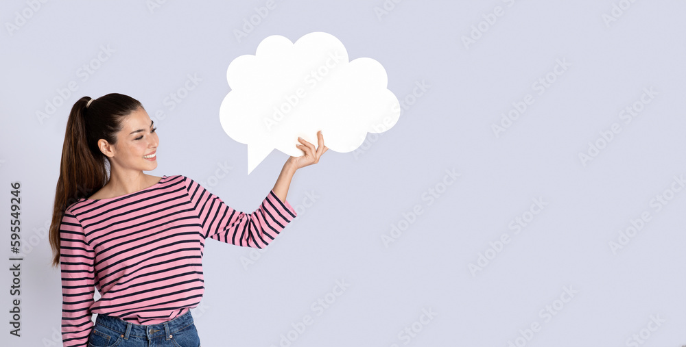 Cheerful pretty young woman holding white conversation bubble, copy space Cheerful pretty young woman holding white conversation bubble, copy space