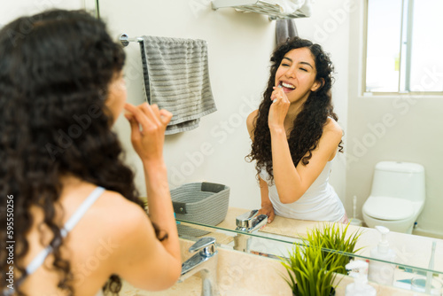 Attractive woman flossing and brushing her teeth