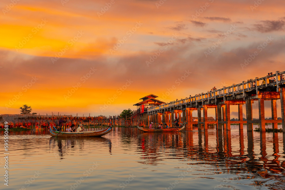 Unidentified people walk on U Bein bridge at sunset in Myanmar. U Bein bridge is the longest teak bridge in the world, Amarapura, Myanmar