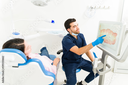Man dentist explaining the teeth 3d model to a patient for an orthodontics treatment