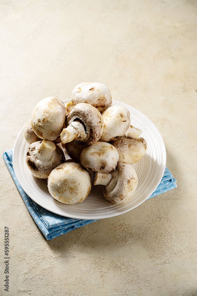 Raw champignon mushrooms in a plate. Fresh vegetables for cooking. Raw champignon mushrooms in a plate. Fresh vegetables for cooking.