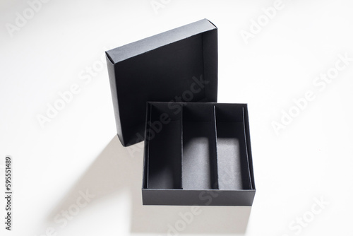 Black cardboard box open on white background, mock up for design branding. Opened box for small items and chocolate candies