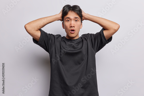 Foto Waist up shot of emotional Chinese man with dark hair hears unexpected shocking