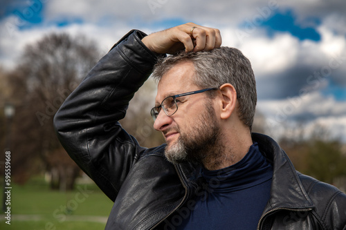Portrait of a middle aged man in eyeglasses and leather jacket in the park