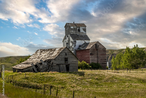 Rustic buildings and grain elevator stand in what used to be the town of Sharples Alberta Canada