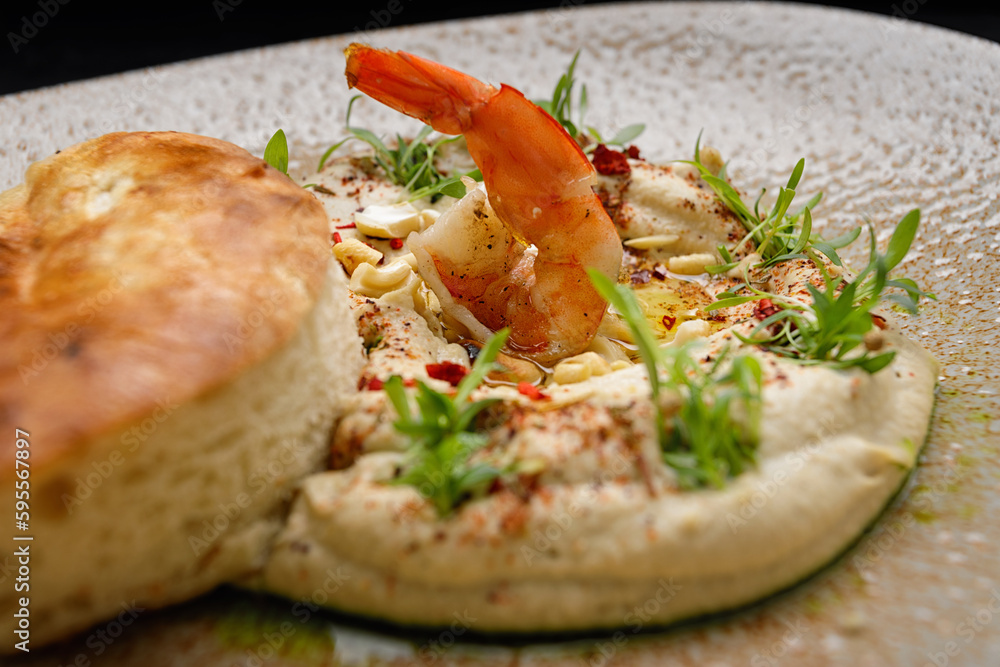 Hummus with shrimp, peanuts, chickpeas and a bun, on a plate Hummus with shrimp, peanuts, chickpeas and a bun, on a plate