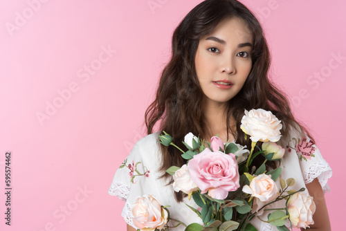 Young Asian woman holding a rose bouquet on hand isolated pink color background