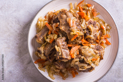 Close up of stewed oxtail with carrots and onions on a plate on the table top view