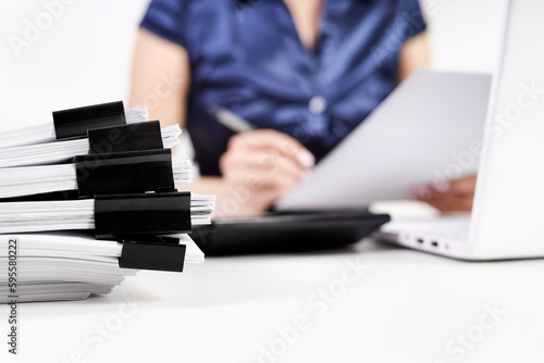 A stack of papers with Binder Clips against the background of an office worker working with documents