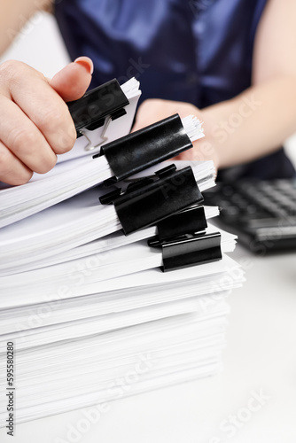 An office worker sorts out a stack of papers fastened with Binder Clips