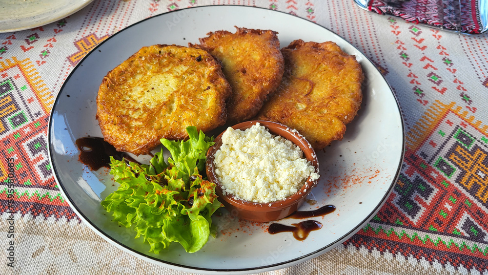 Delicious craft potato dumplings with homemade brynza cheese and greens on a plate against the background of national towels, traditional Ukrainian cuisine