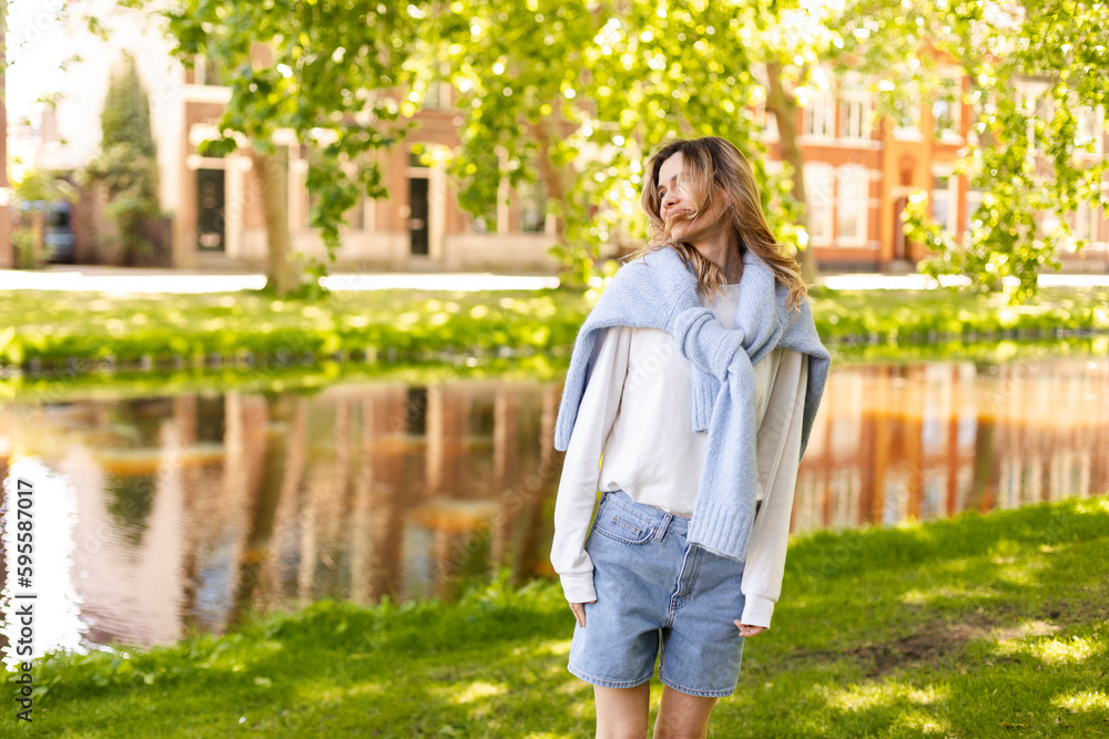 Portrait of beautiful woman smiling and look at side in park at sunny day. Outdoor portrait of a smiling curly blonde girl. Happy cheerful girl laughing at park wear sweater, white longsleeve, short. Portrait of beautiful woman smiling and look at side in park at sunny day. Outdoor portrait of a smiling curly blonde girl. Happy cheerful girl laughing at park wear sweater, white longsleeve, short.