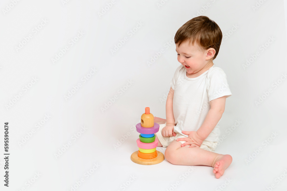 Happy baby play educational toys on studio white background. Portrait of a smiling child playing while sitting on the floor. Kid about two years old (one year nine months) Happy baby play educational toys on studio white background. Portrait of a smiling child playing while sitting on the floor. Kid about two years old (one year nine months)