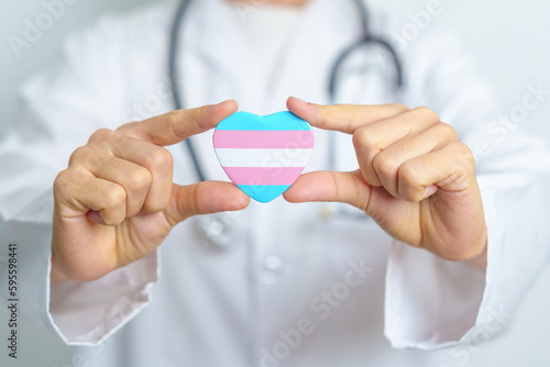 Transgender Day and LGBT pride month, LGBTQ+ or LGBTQIA+ concept. Doctor holding blue, pink and white heart shape for Lesbian, Gay, Bisexual, Transgender, Queer and Pansexual community