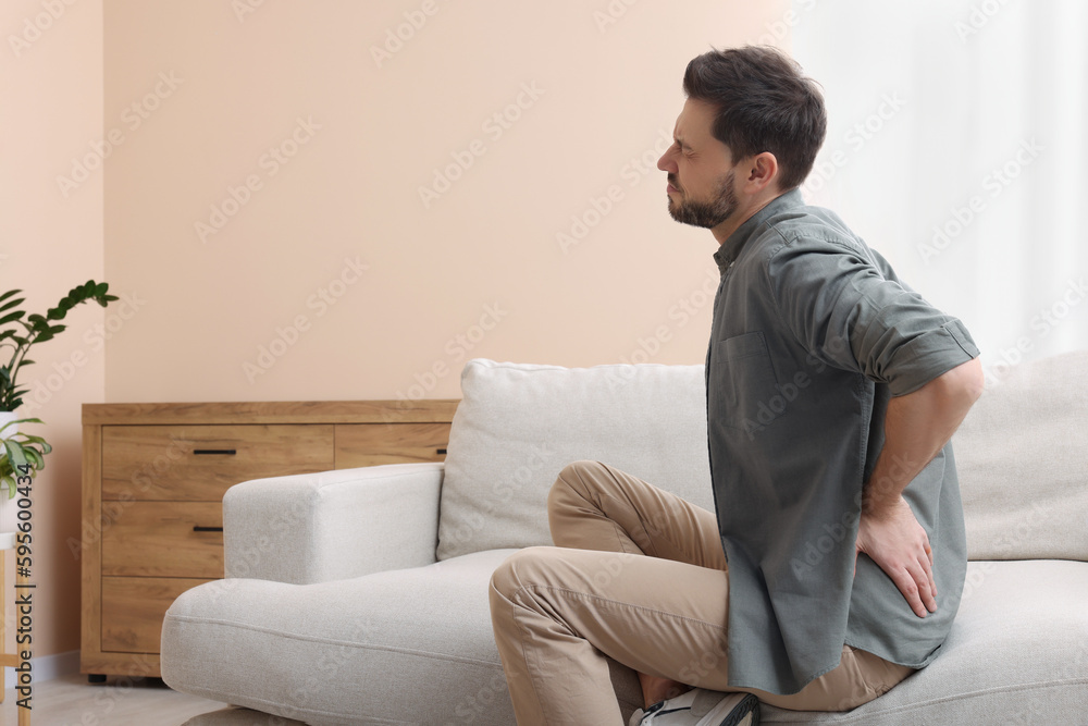 Man suffering from pain in his back at home, space for text. Arthritis symptoms