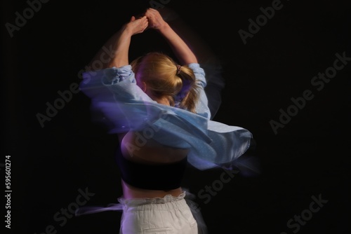 Young woman performing contemporary dance on black background, motion blur effect