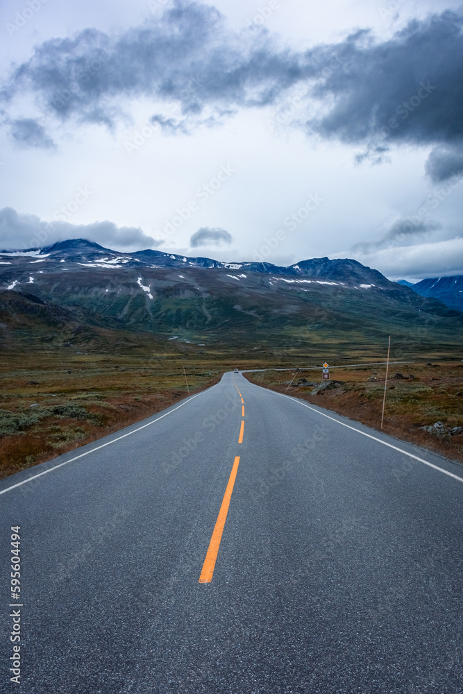 Empty road through the tundra of central Norway with cloudy and  moody sky