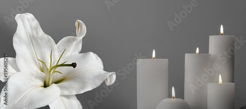 Funeral. White lily and burning candles on grey background, banner design