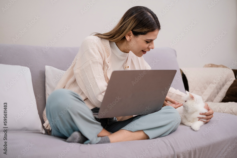 Working woman sitting on coach with her cat, Freelance girl doea work while feeding snack to her kitten. Working woman sitting on coach with her cat, Freelance girl doea work while feeding snack to her kitten.