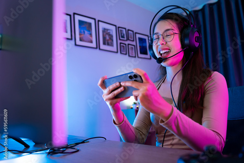 Asian modern female gamer having serious gaming fun in a RGB-lit gaming room.