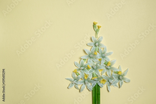 Christmas tree creative of white flowers on a light yellow background. concept of flowers Christmas tree and copy space