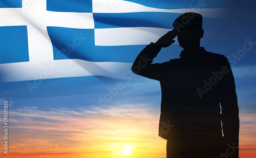 Silhouette of a saluting soldier with Greece flag against the sunset sky