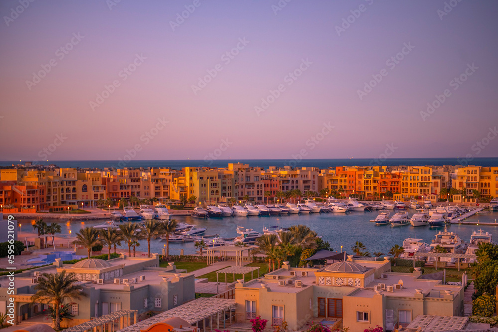 Obraz premium Stadtbild von El Gouna, Ägypten, vom Marina Hill aus mit nubischen Häusern, Yachten und Booten zum Sonnenuntergang