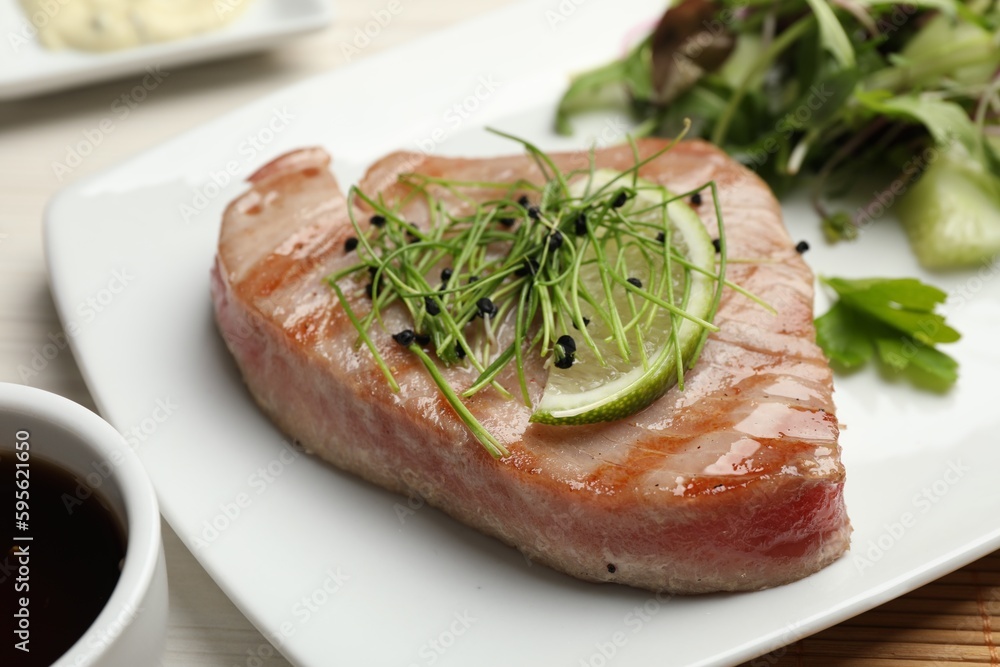 Delicious tuna steak with microgreens and lime on plate, closeup Delicious tuna steak with microgreens and lime on plate, closeup