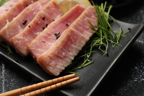 Pieces of delicious tuna steak served on black table, closeup