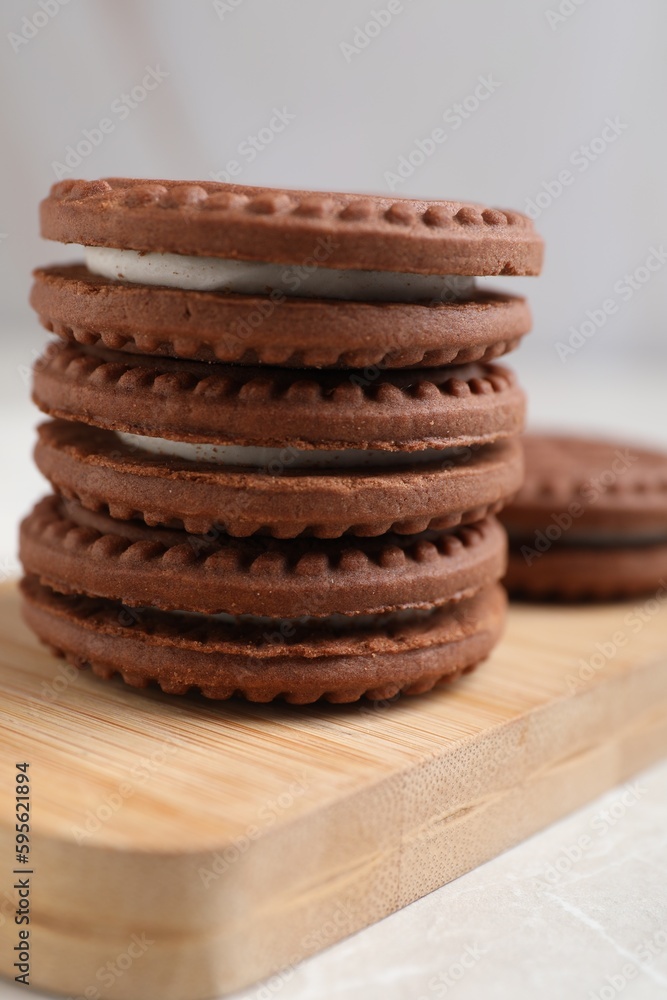Tasty chocolate sandwich cookies with cream on wooden board, closeup Tasty chocolate sandwich cookies with cream on wooden board, closeup