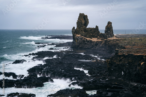 Lóndrangar is a unique geological formation located on the Snæfellsnes Peninsula in Iceland. These two volcanic basalt cliffs rise dramatically from the surrounding landscape and are a popular spot.  photo