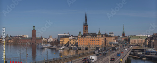 Train, trams and cars passing the bridges in the islands of the old town Gamla Stan, a sunny day in Stockholm