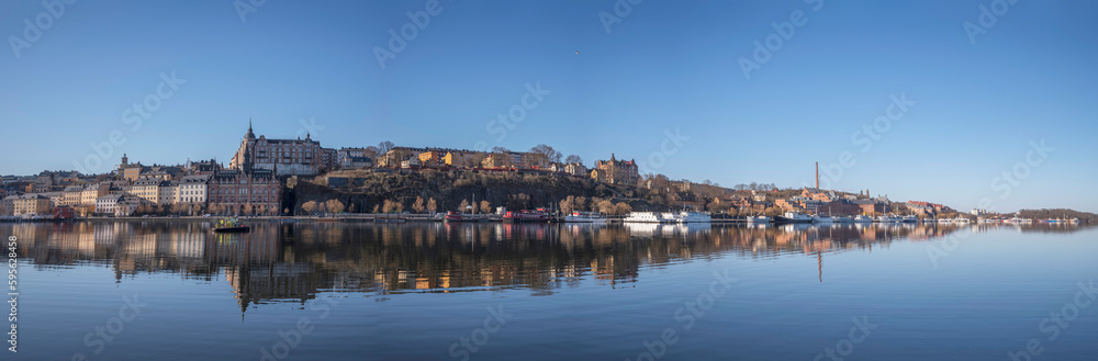 Pier Södermälastrand, cliffs Mariaberget, Skinnarviksberget, old 1700s houses brick factory building, waterfront, cargo, fish and hotels ships, a tranquil sunny spring day, Stockholm Sweden 2023-04-21