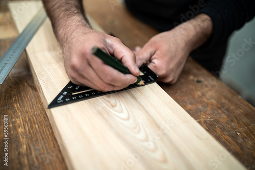Carpenter holding a set square on the work bench