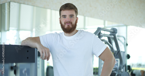 Portrait of fit athletic young bearded man in gym  fitness trainer  coach.