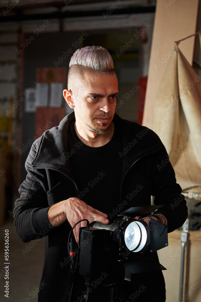 a young caucasian gafer installs a lighting fixture on a movie set a young caucasian gafer installs a lighting fixture on a movie set