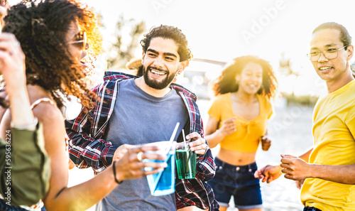 Young guys and girls dancing at sunset concert on summer vacation days - Fancy life style concept with friends having genuine fun day together at spring break festival beach party - Warm bright filter