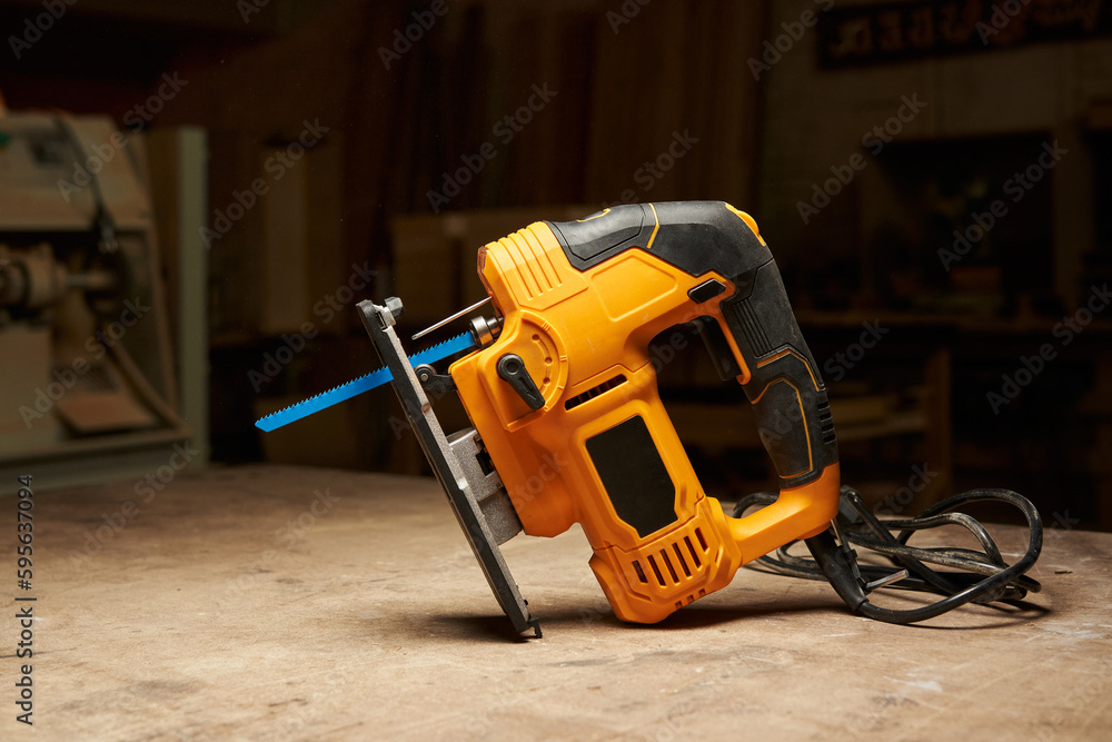 a beautiful black and yellow electric jigsaw with a blue saw blade stands on a wooden workbench in a workshop a beautiful black and yellow electric jigsaw with a blue saw blade stands on a wooden workbench in a workshop