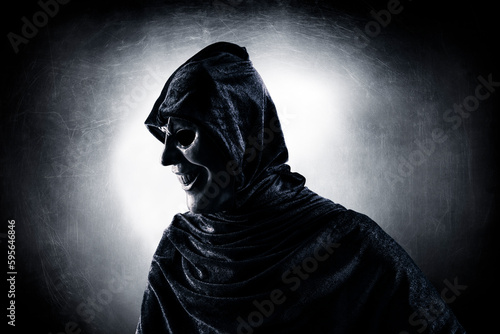 Scary figure with hooded cloak in the dark