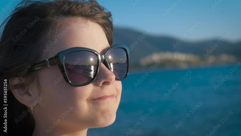 Sunset reflection in child's sunglasses. Portrait of a little girl in sunglasses looking at the sea sunset.