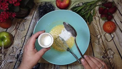 Female chef putting baking povder into the pancake mix. Food preparation concept. High quality 4k footage photo