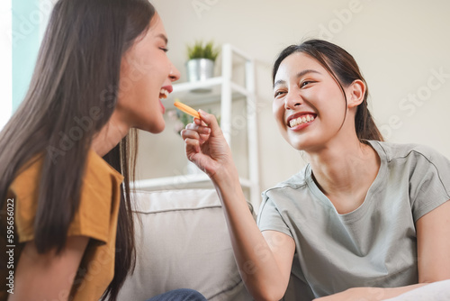 Happy lesbian, pleasure two asian young women, girl gay or close friend, couple love , moment spending good time together on sofa at home. Activity of leisure, relax.