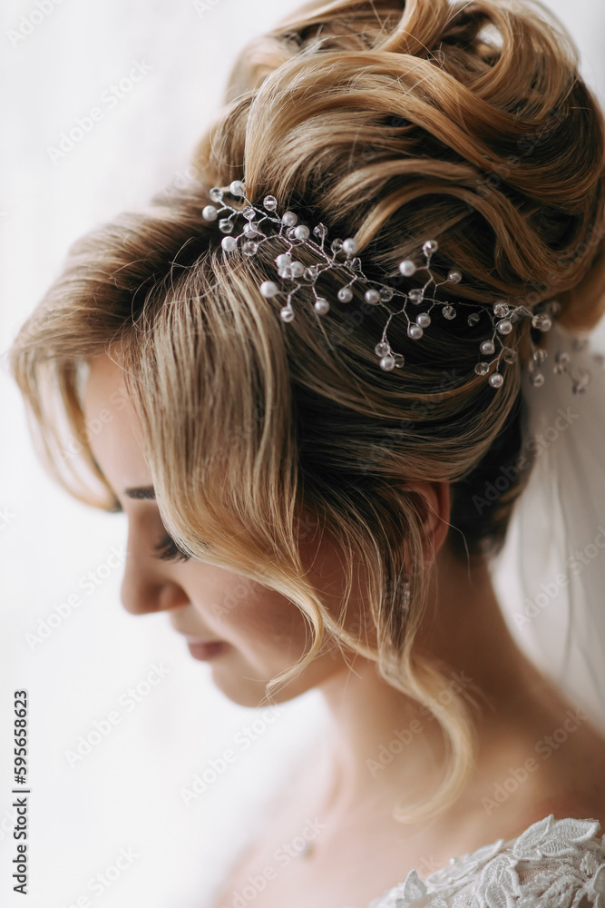 Naklejka premium Wedding details. Photo of an elegant hairstyle of a blonde bride. Beautiful curls. Beautiful hair and makeup. Diadem